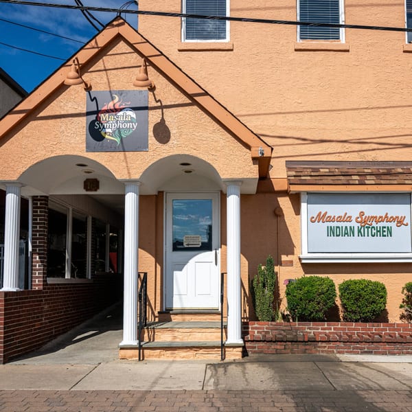 Exterior of Masala Symphony Indian Kitchen, an orange building with a white door and arched entrance.