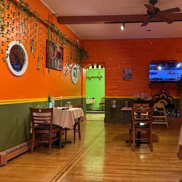 Masala Symphony dining room with orange and green walls, hardwood floors, and set tables.