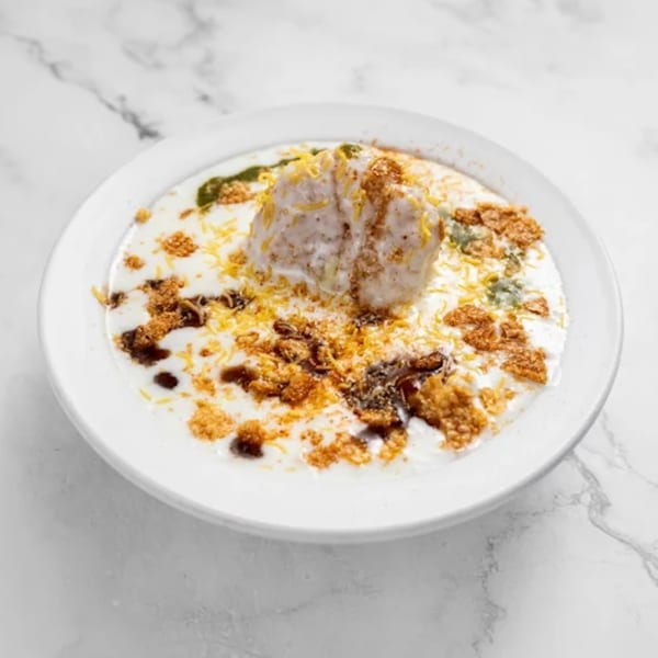 Dahi Bhalla from Masala Symphony, a white lentil dumpling in yogurt, topped with chutneys and spices.